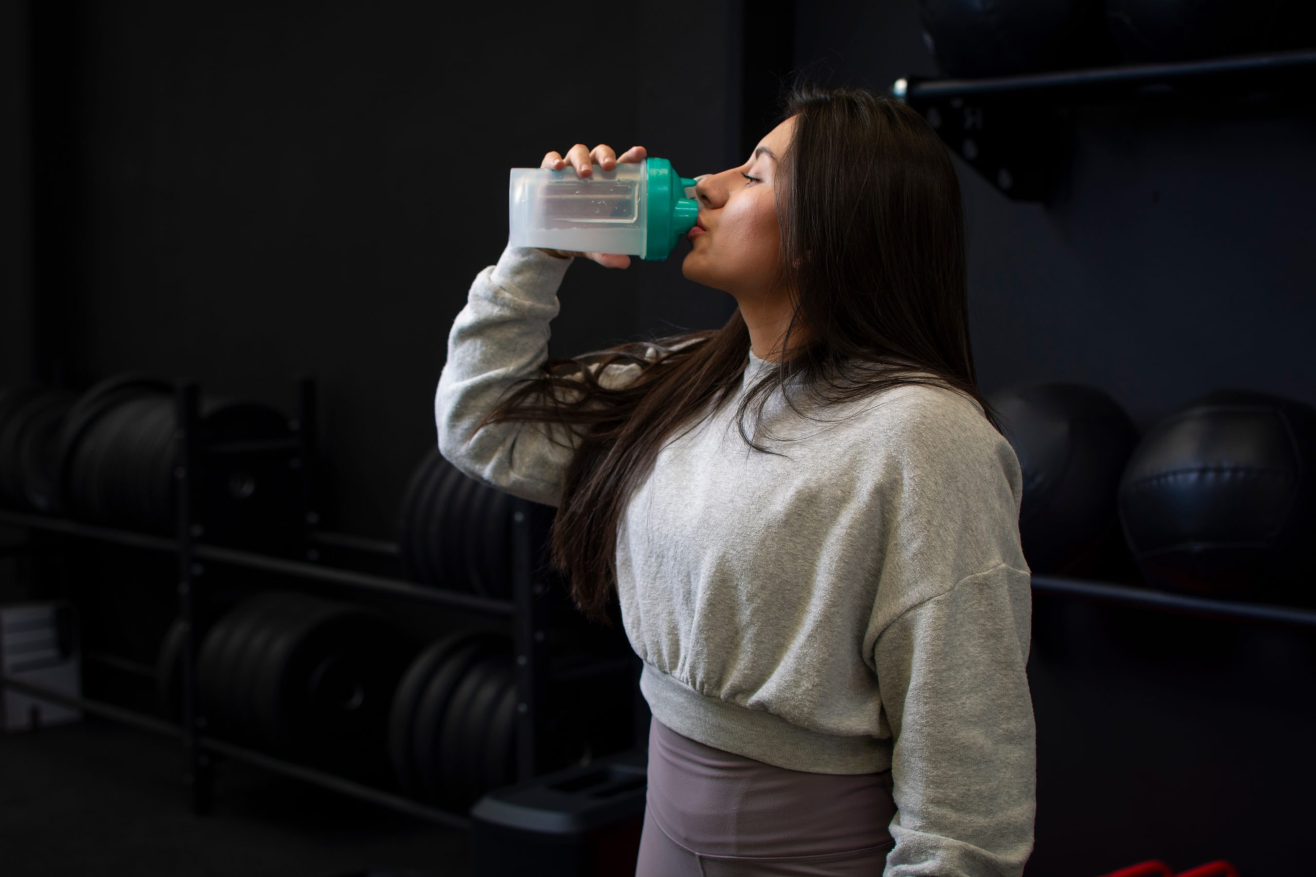 Close up of a woman taking protein from her shaker at the gym